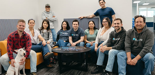 Group of Fortera staff smiling at the camera while sitting around a table with an unfinished jigsaw puzzle on it