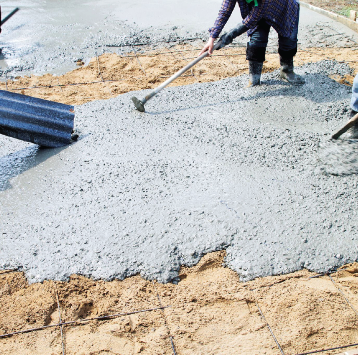 Worker spreading freshly poured concrete from a truck